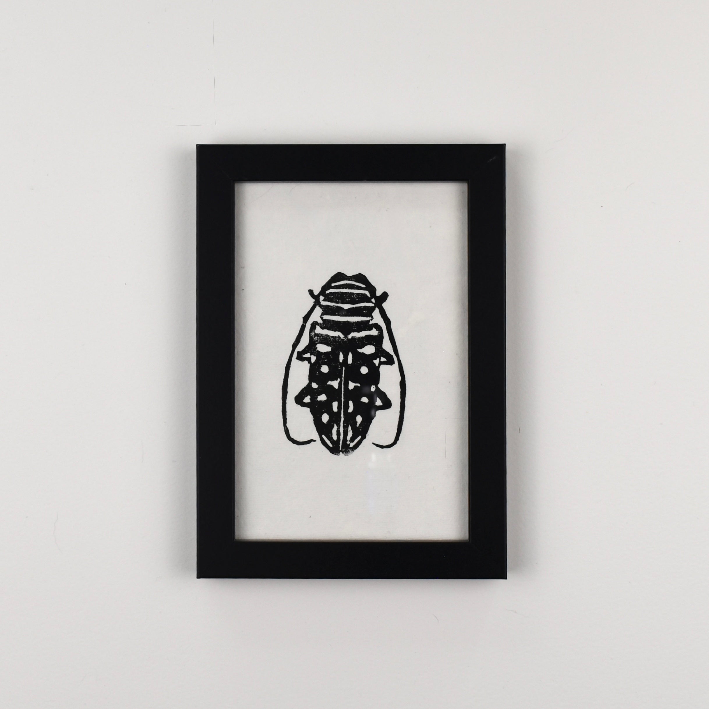 Hand-printed black and white linocut art of an African longhorn beetle, framed
