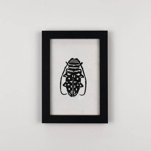 Hand-printed black and white linocut art of an African longhorn beetle, framed