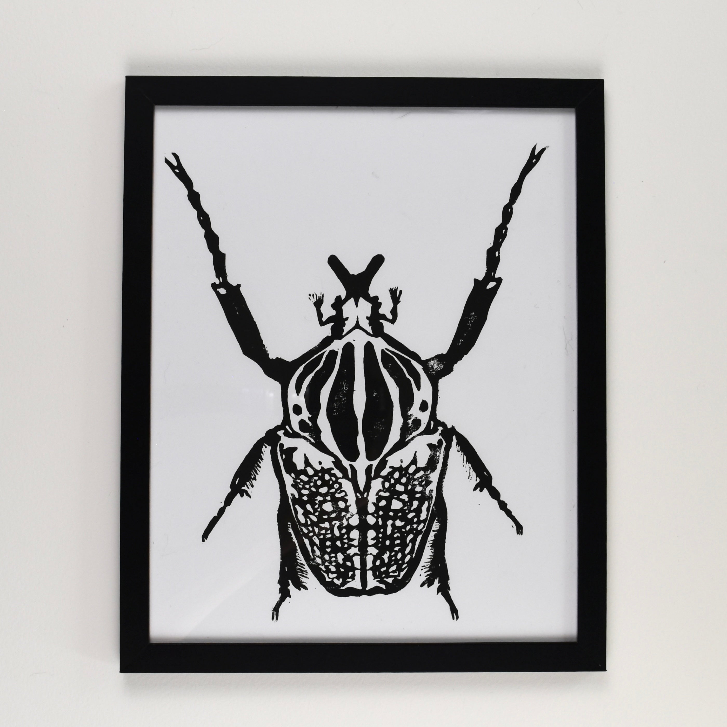Hand-printed black and white linocut art of a goliath beetle, framed