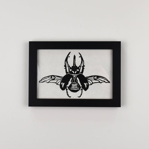 Hand printed black and white linocut of an Atlas beetle, framed